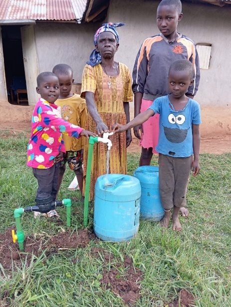 A grandmother and children at a household tap